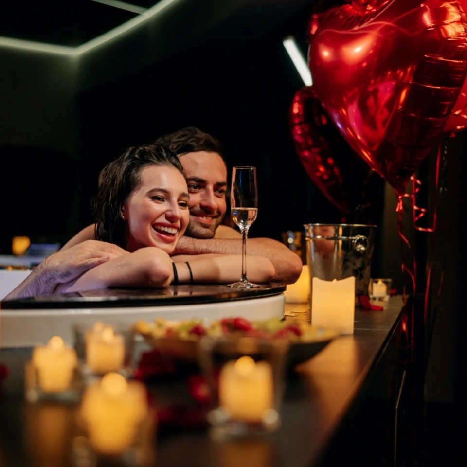 Para w jacuzzi, czerwone balony i świece
