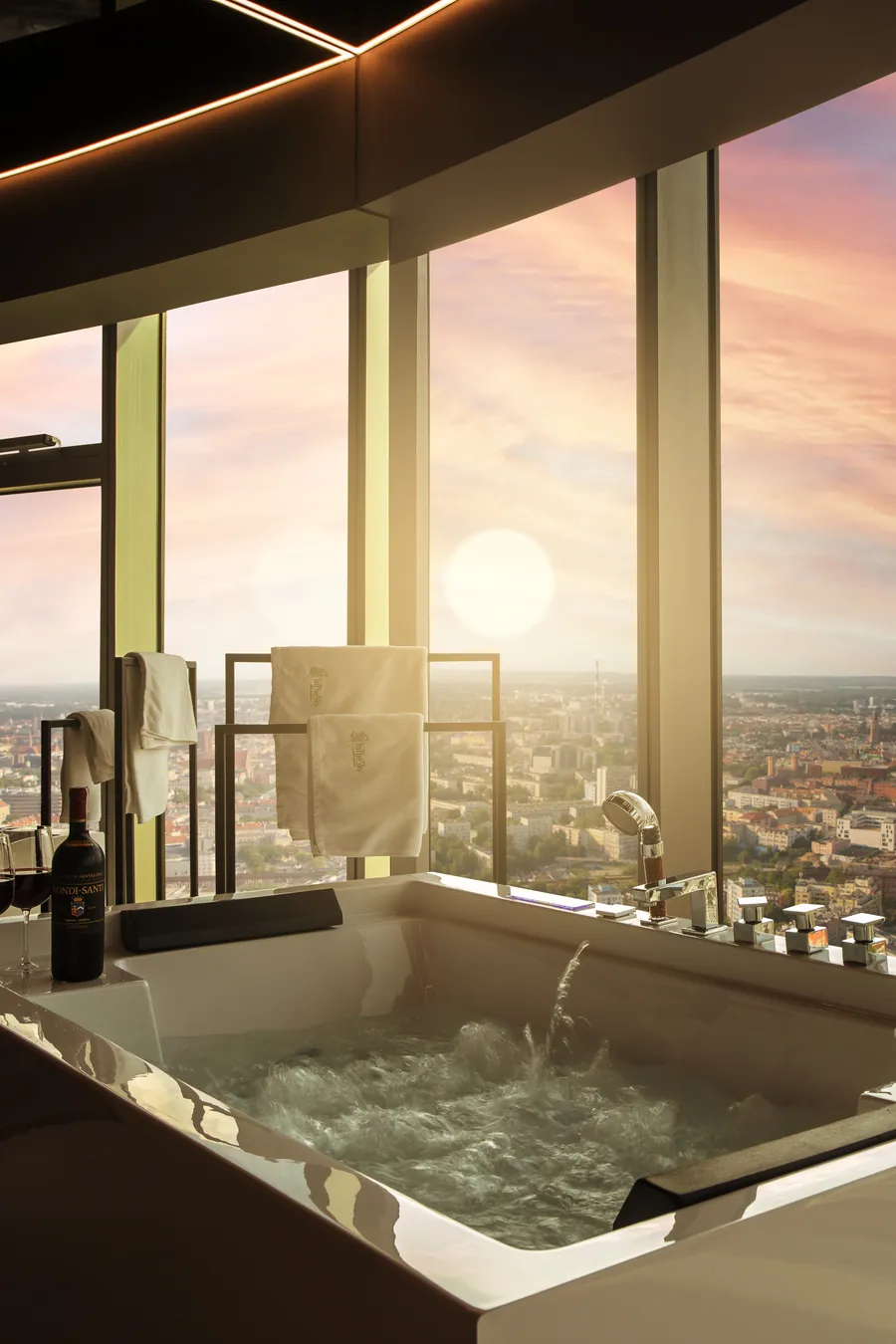 Apartament In The Sky w Sky Tower - jacuzzi przy panoramicznym oknie z widokiem na Wrocław o zachodzie słońca