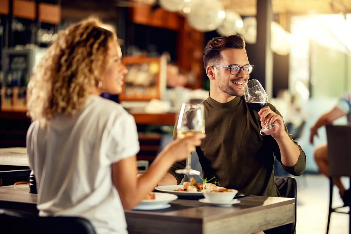 Pár při večeři v restauraci se skleničkami vína v rukou